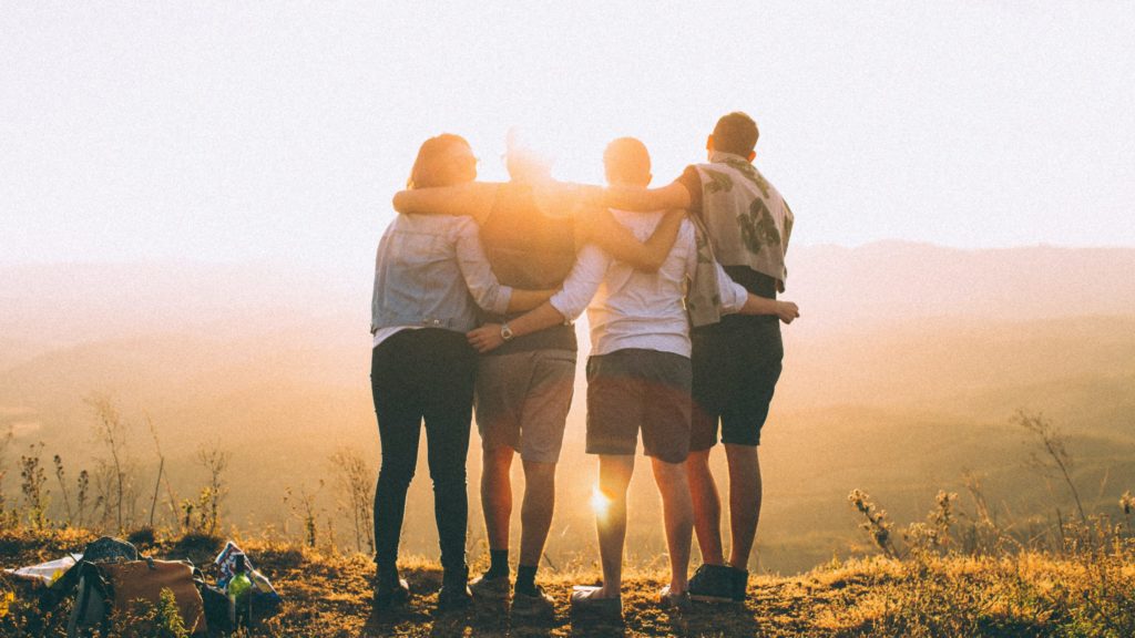 Youth standing with arms around each other looking into the sunrise