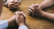 several hands clasped in prayer