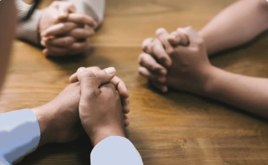 several hands clasped in prayer